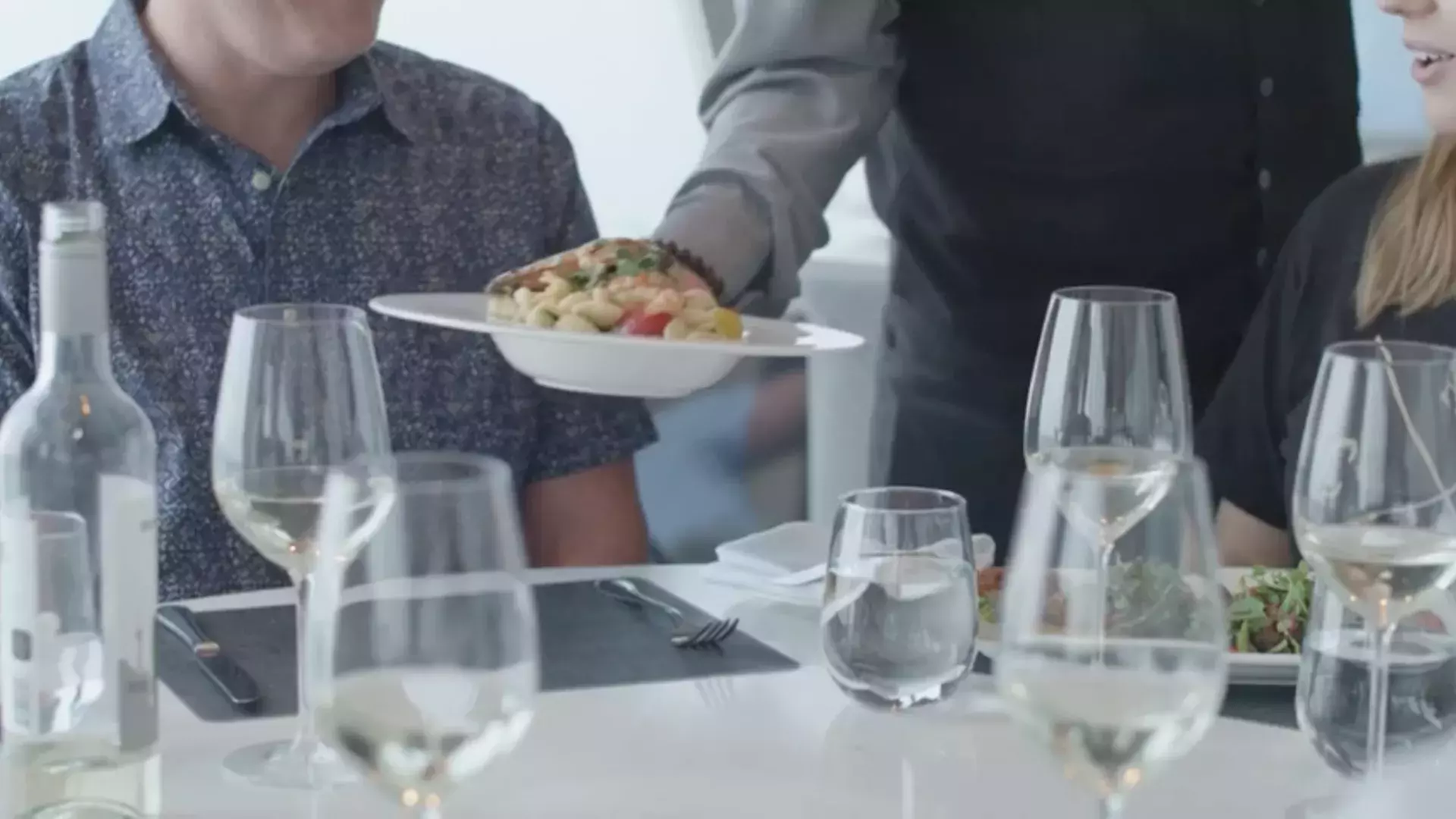 Server delivering dish to restaurant customer sitting at table.