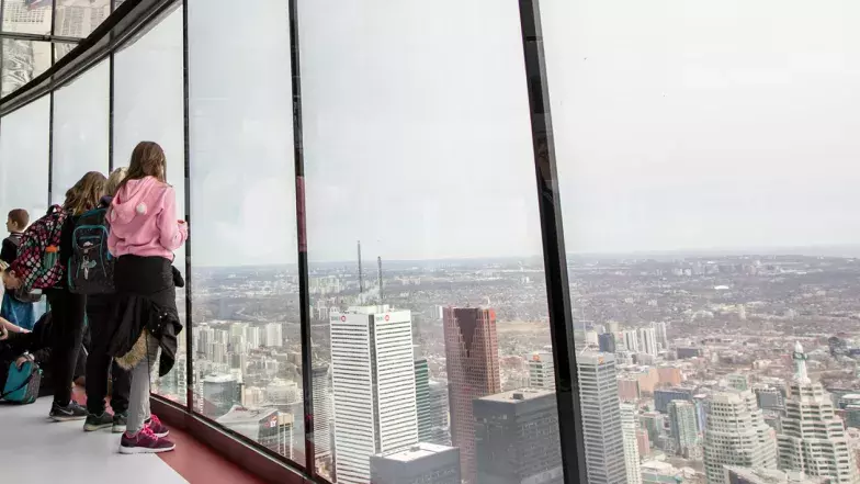 A group of young people with backpacks at the window of the observation deck