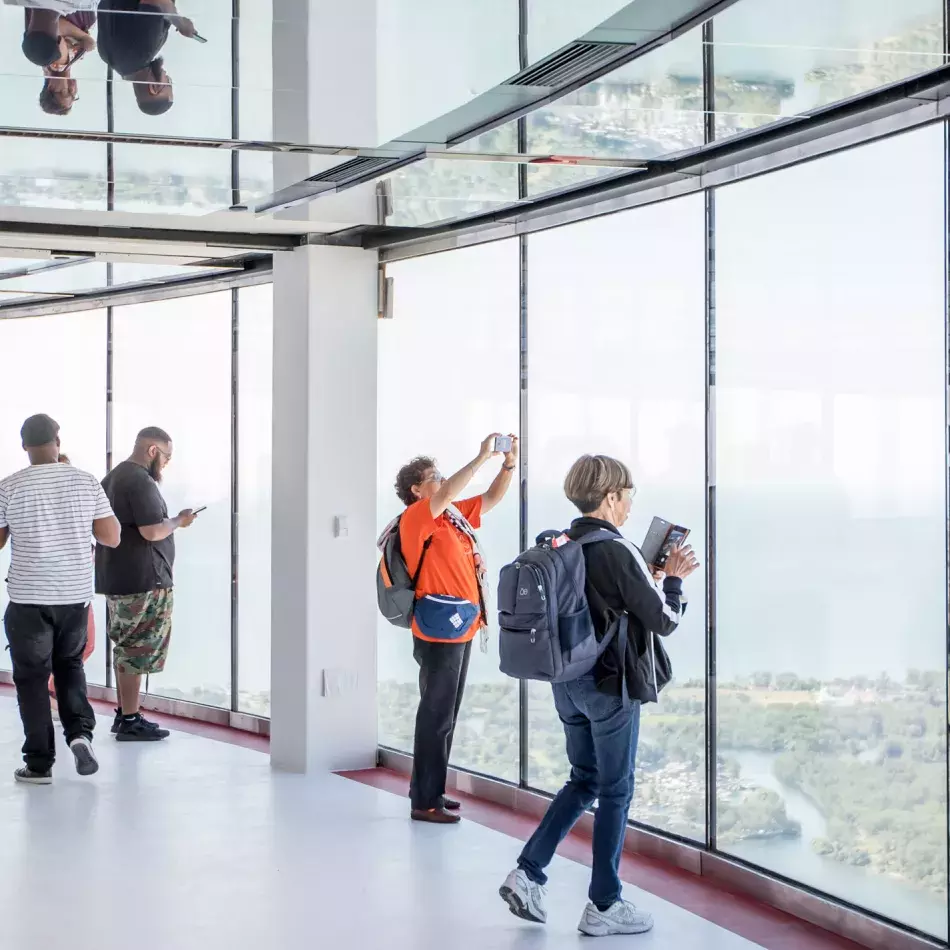 Two people looking out the window. Holding cell phones in their hands to take photo