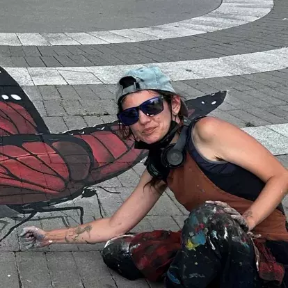 jo the chalk chick crouching down next to their 3D butterfly mural