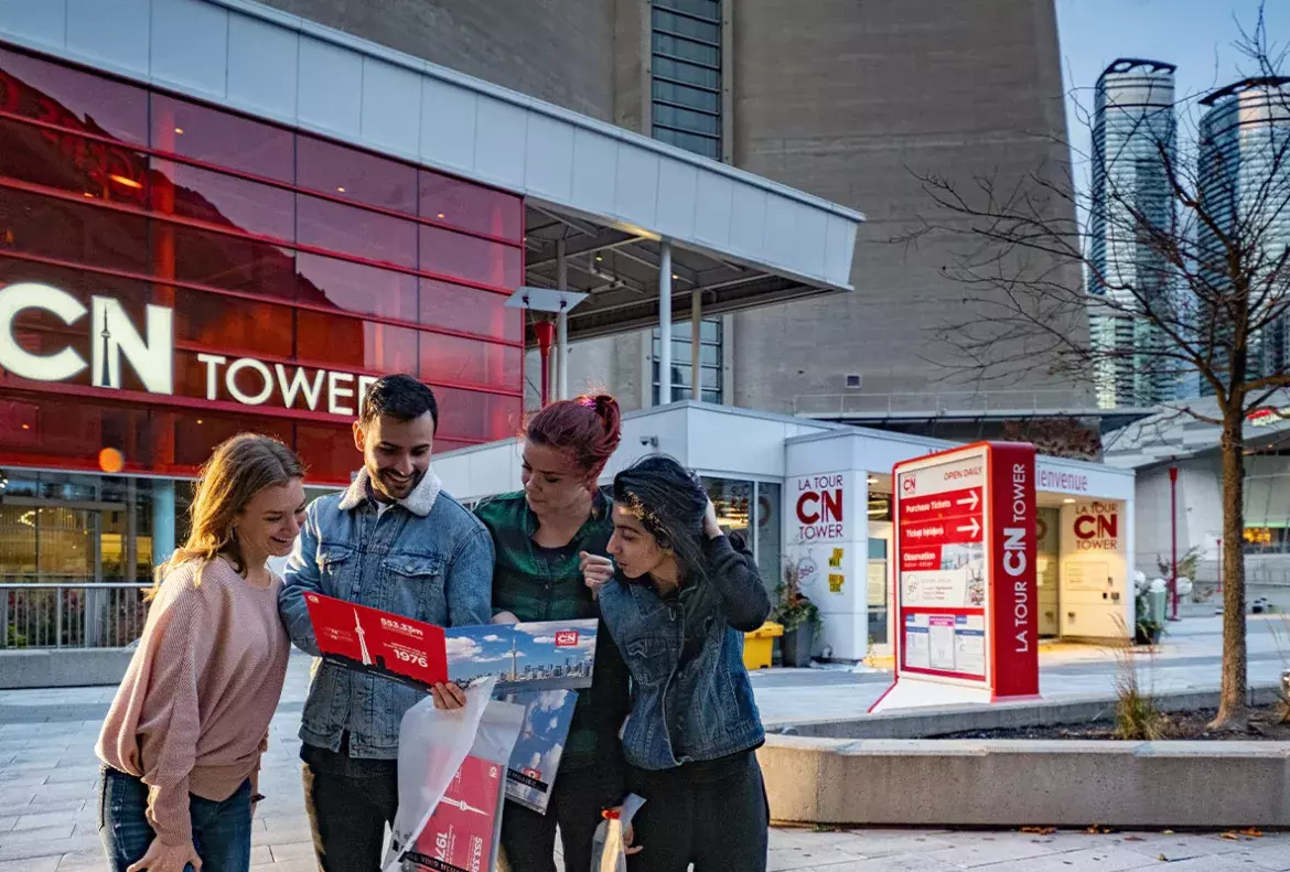 Four young people outside CN Tower reviewing the tower photo package