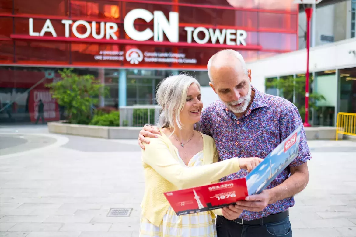 A couple looking at their souvenir photos outside the CN Tower.