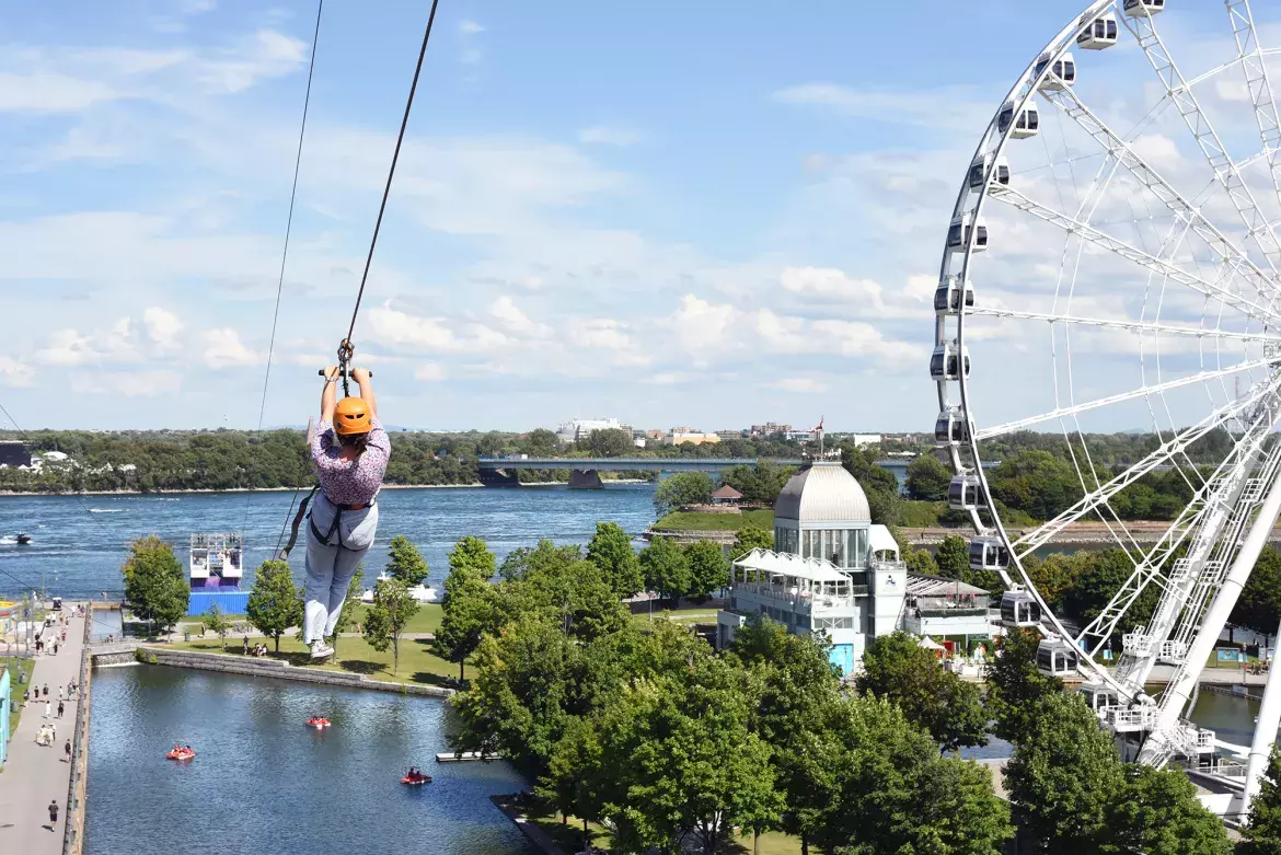 A person going down a zipline by the Old Port of Montréal’s Ferris Wheel.